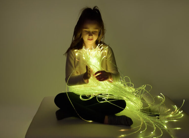 Playlearn product, young girl intrigued by glowing fiber optic product