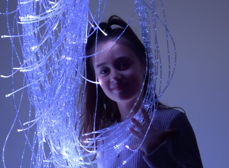Playlearn young girl intrigued by glowing fiber optic product